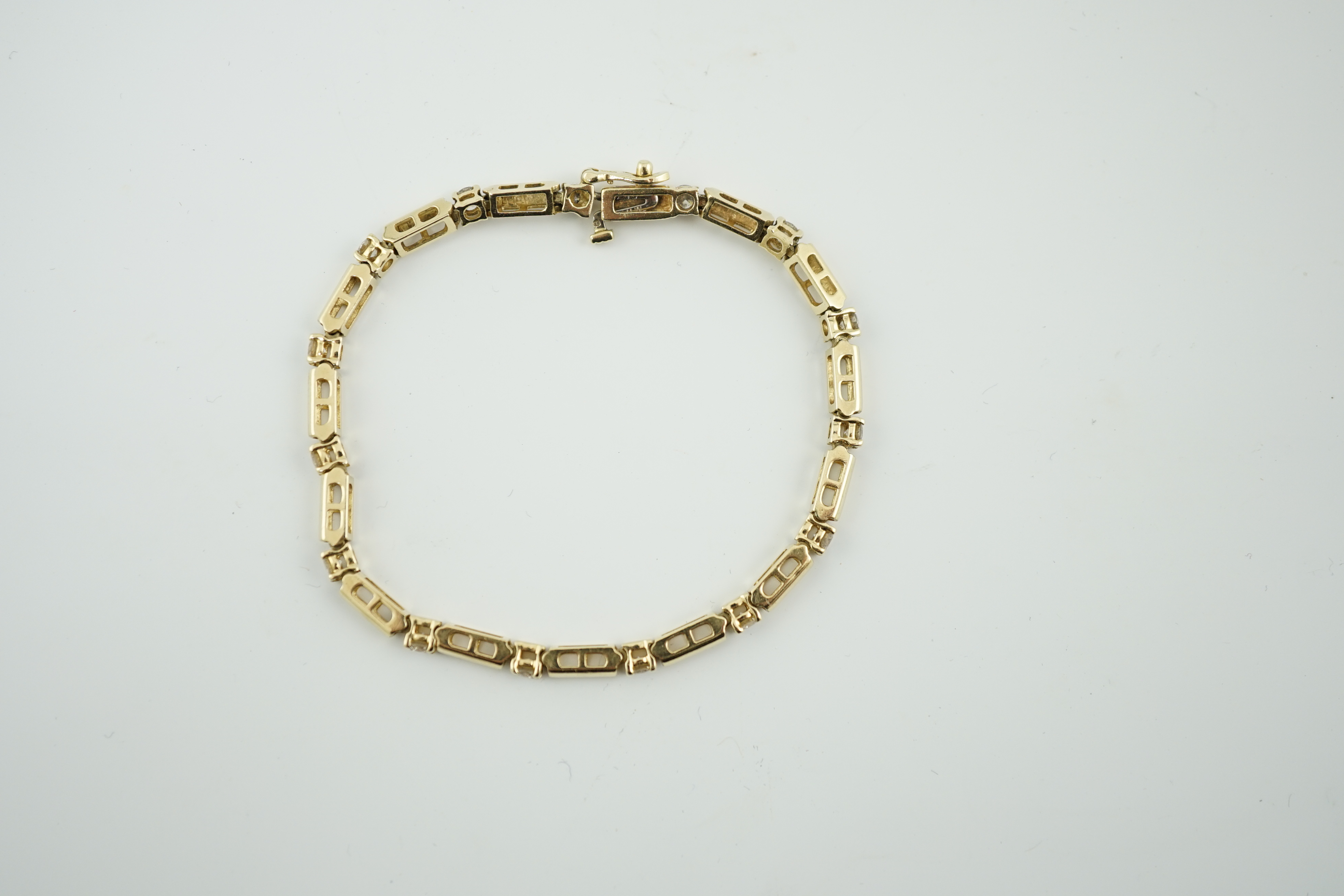 A modern 14k gold and fifteen stone diamond set line bracelet